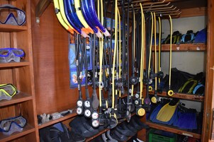 A storage area with shelves holding various diving equipment, including fins, masks, and gauges.