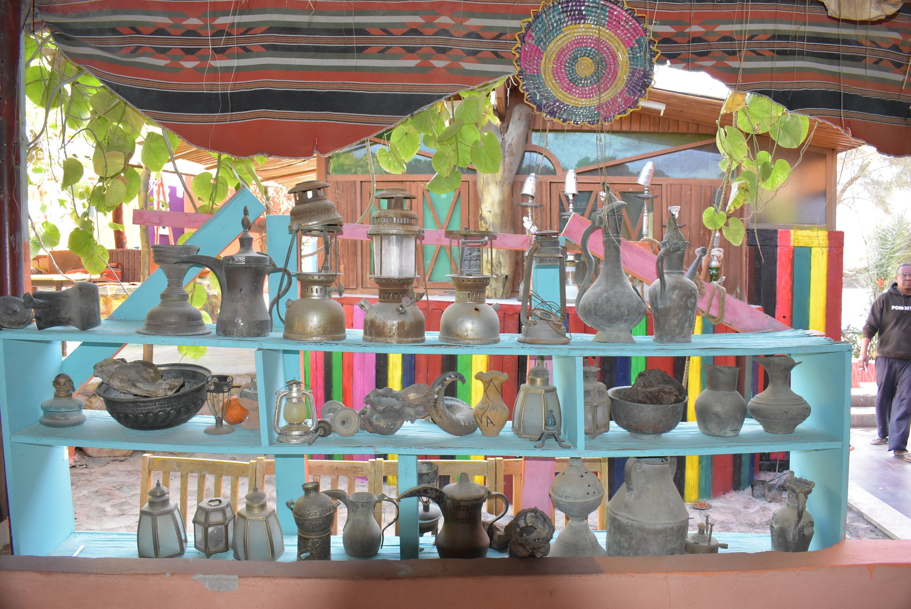 A display of various metal containers and utensils on a blue shelf.