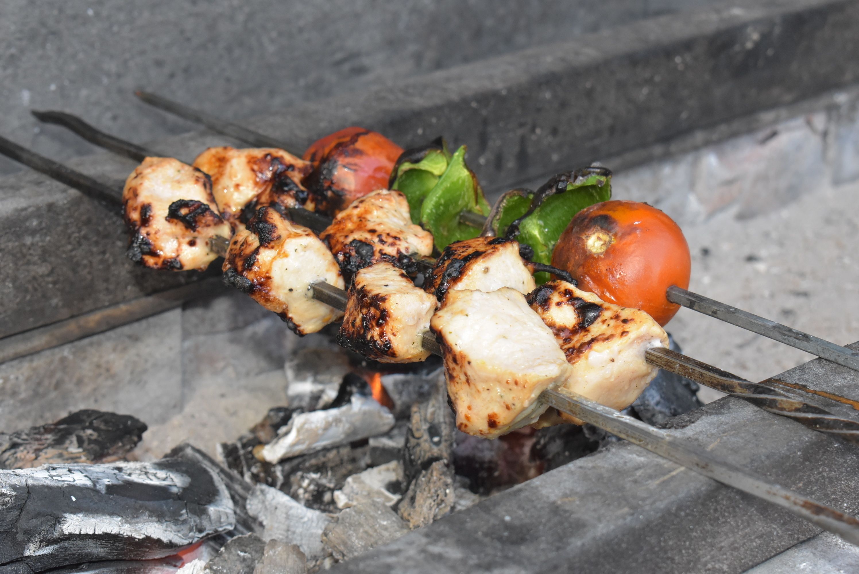 Skewers of grilled chicken and vegetables over an open flame.