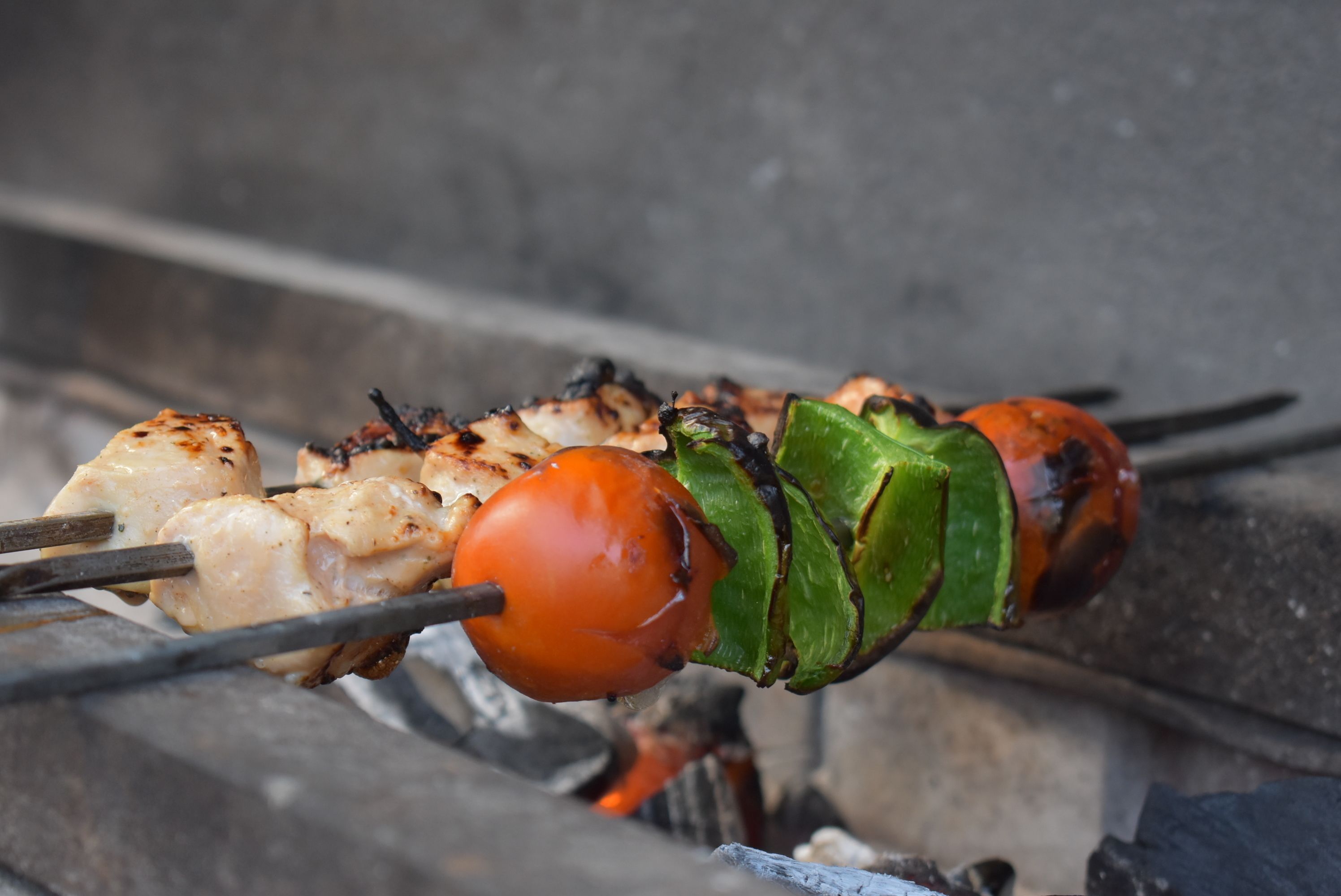 Skewers of grilled chicken and vegetables on a grill.