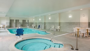 Ein Hallenbad mit blauem Stuhl, weißen Liegestühlen und einem Tisch mit Sitzgelegenheiten.