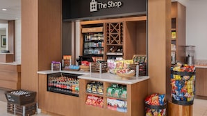 Ein Geschäft namens 'The Shop' mit Kühlregalen, einer Auswahl an Snacks und verschiedenen abgefüllten Getränken.