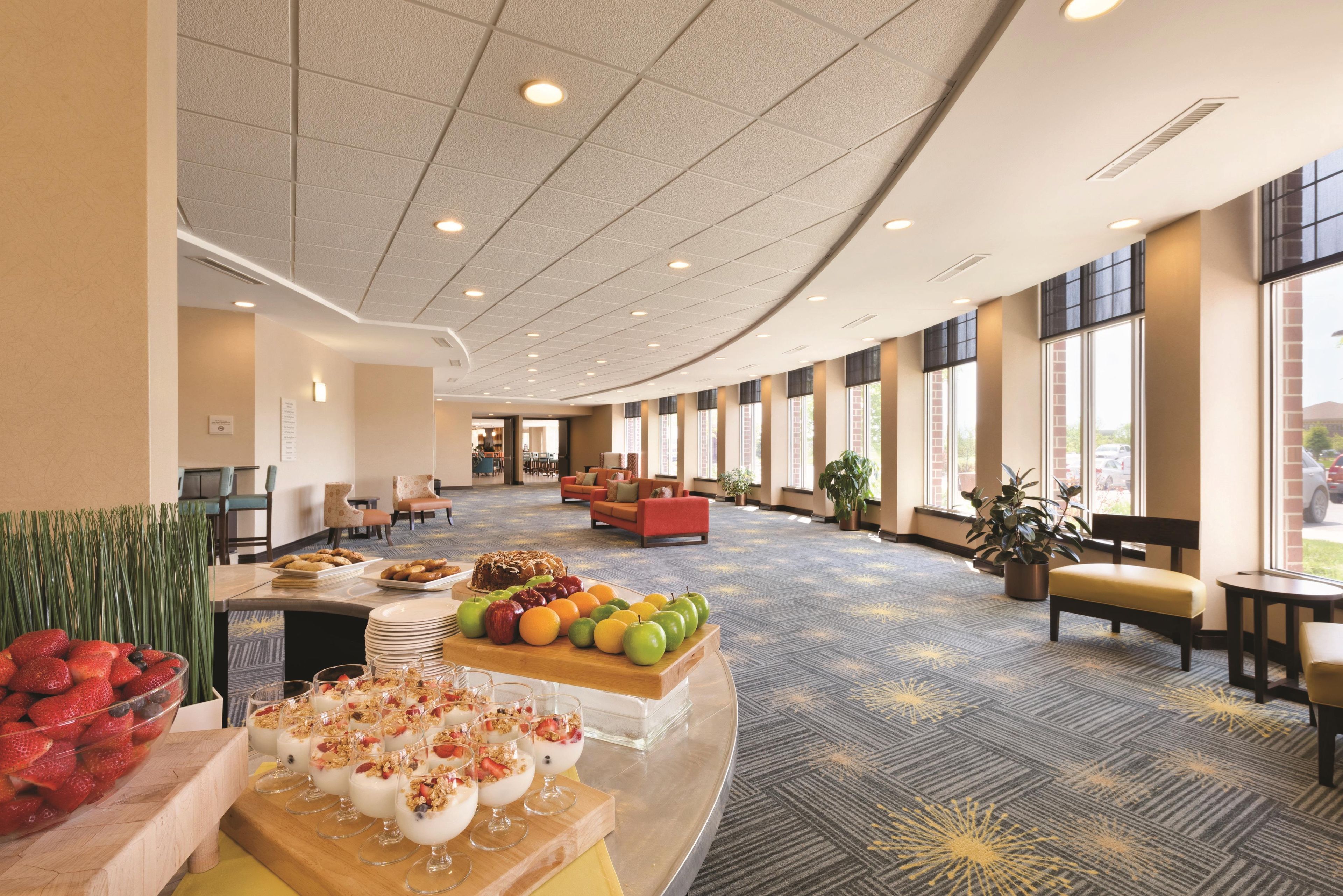 Un hall d’hôtel avec un espace buffet, des sièges et de grandes fenêtres.