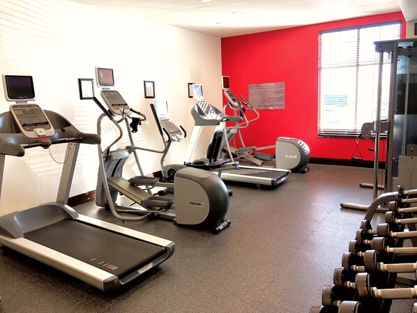 Un gimnasio con cintas de correr, elípticas y mancuernas.