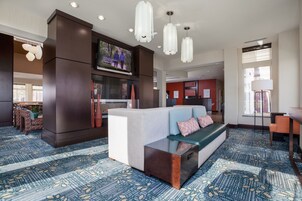 Un moderno vestíbulo de hotel con un amplio espacio de estar, un televisor de pantalla plana y una alfombra estampada.