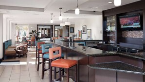 A modern bar area with seating, a television screen, and a tiled floor. - Hilton Garden Inn Fargo (Fargo)