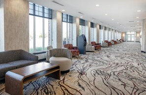 A hotel lobby with a long row of seating, a self-service kiosk, and large windows. - Hilton Garden Inn Fargo (Fargo)
