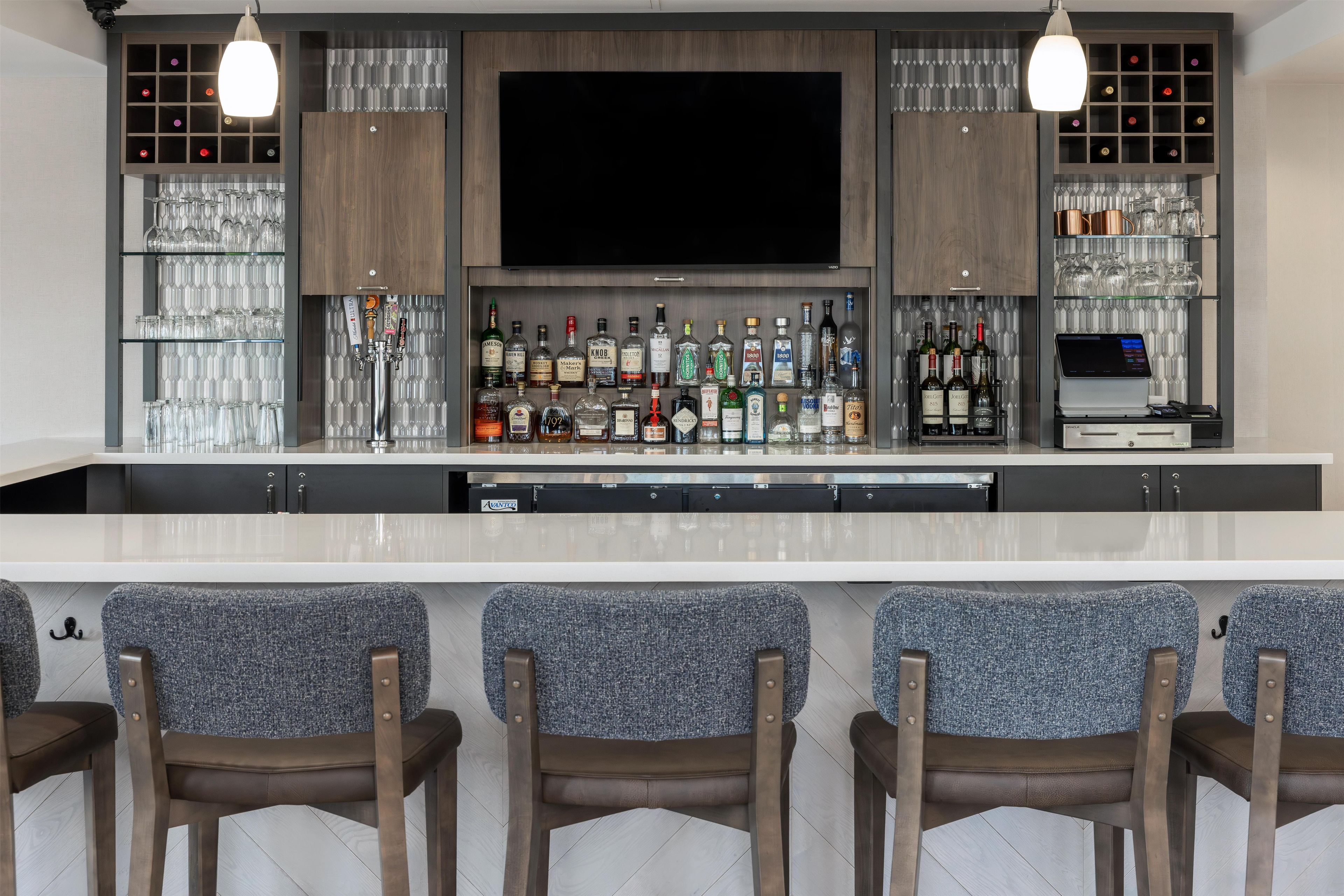 A bar area with a flat-screen TV, multiple liquor bottles, and a wine cooler.