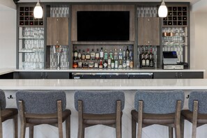 A bar area with a flat-screen TV, multiple liquor bottles, and a wine cooler. - Hilton Garden Inn Fargo (Fargo)