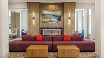 A modern living room with a large sectional sofa, two wooden side tables, a fireplace, and a large abstract painting above the fireplace.