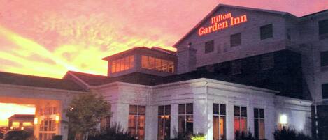 Un hotel Hilton Garden Inn con un diseño arquitectónico moderno, destacando una señalización llamativa y una entrada bien iluminada.