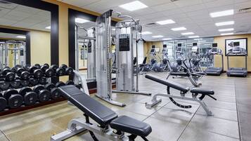 A gym with various exercise equipment, including benches, dumbbells, and cardio machines.