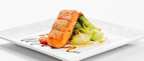 A plate with salmon, green vegetables, and a drizzle of sauce.