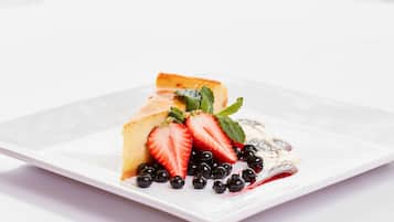 A dessert plate with a slice of cake, strawberries, blueberries, and mint leaves.
