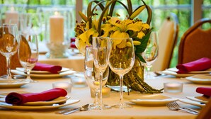 Une table dressée pour un dîner formel, avec de la belle verrerie, des serviettes pliées et un centre de table composé de fleurs jaunes.