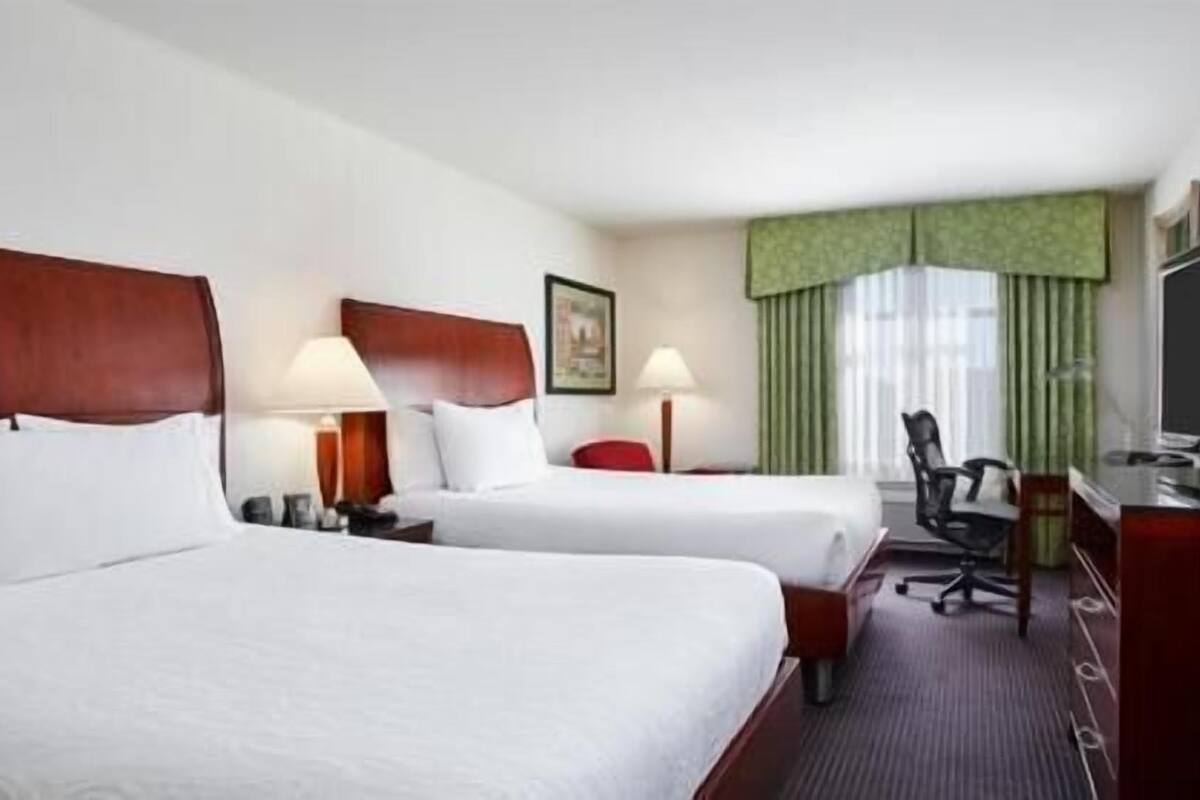 Une chambre d’hôtel avec deux lits, un bureau, une chaise et un téléviseur.