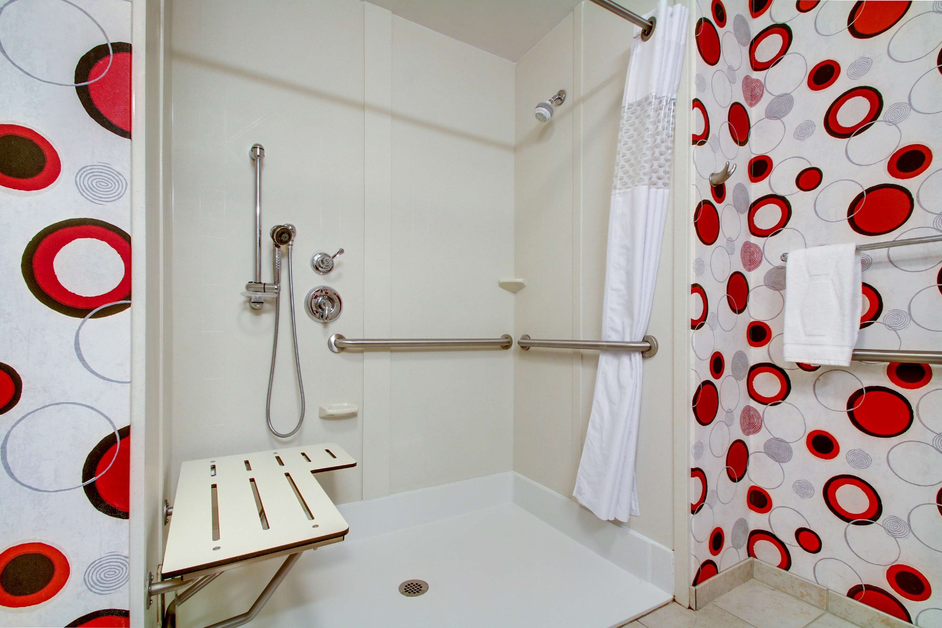 Zona de ducha con pared de azulejos blancos, puerta de cristal y panel de control.