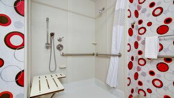 Zona de ducha con pared de azulejos blancos, puerta de cristal y panel de control.