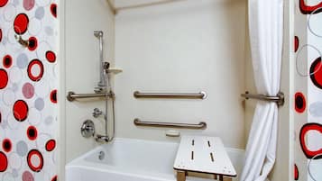 A bathroom with a bathtub, grab bars, and a shower curtain.