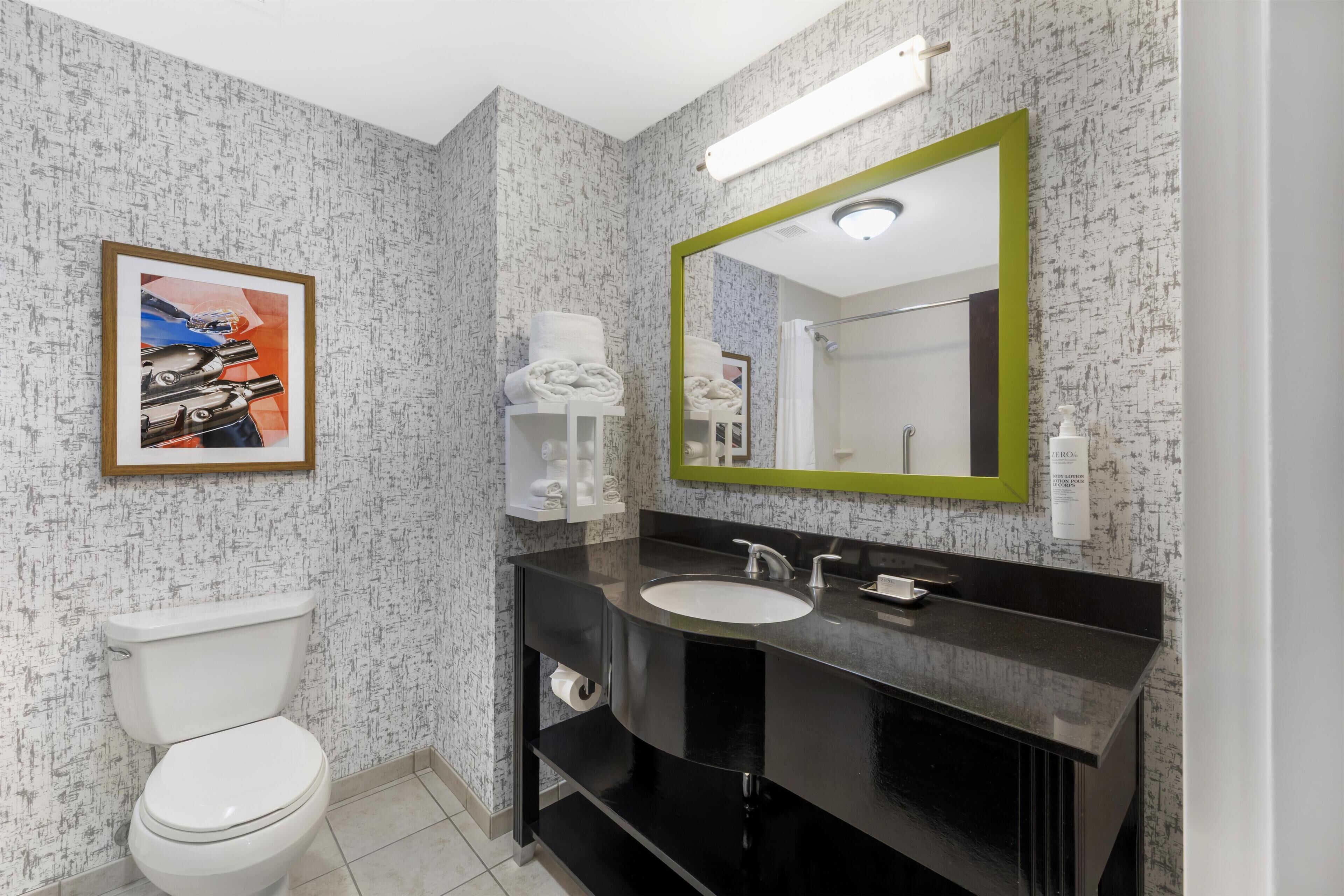 A modern bathroom with a toilet, sink, and mirror.