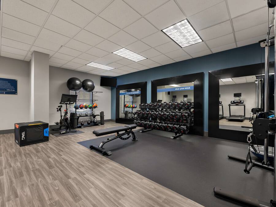 A gym with exercise equipment, a bench, and a wall-mounted mirror.
