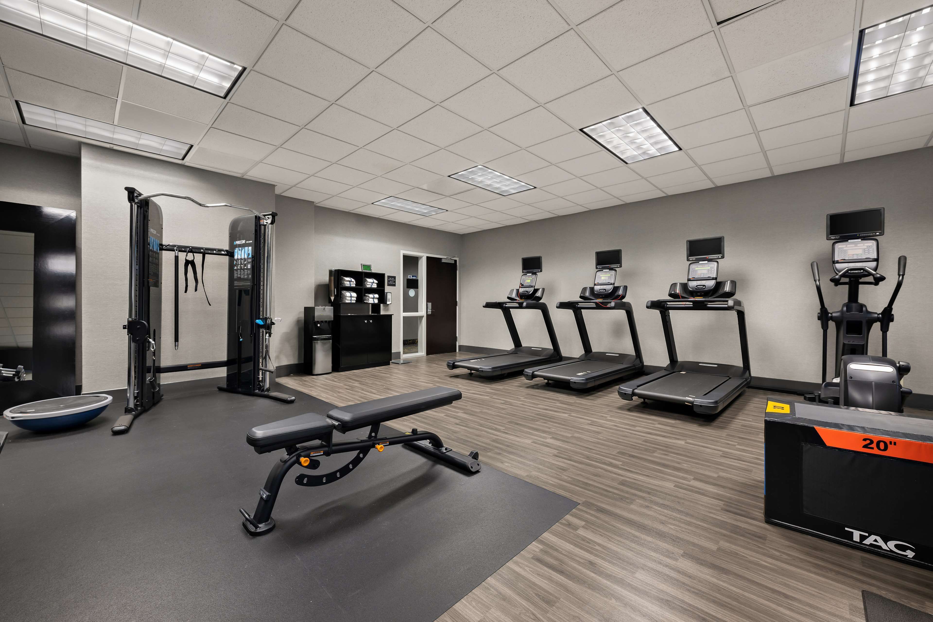 A gym with treadmills, a weight bench, and exercise equipment.
