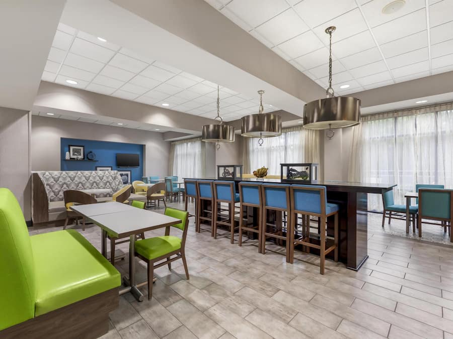 A modern hotel lobby with a bar area, seating arrangements, and a television.