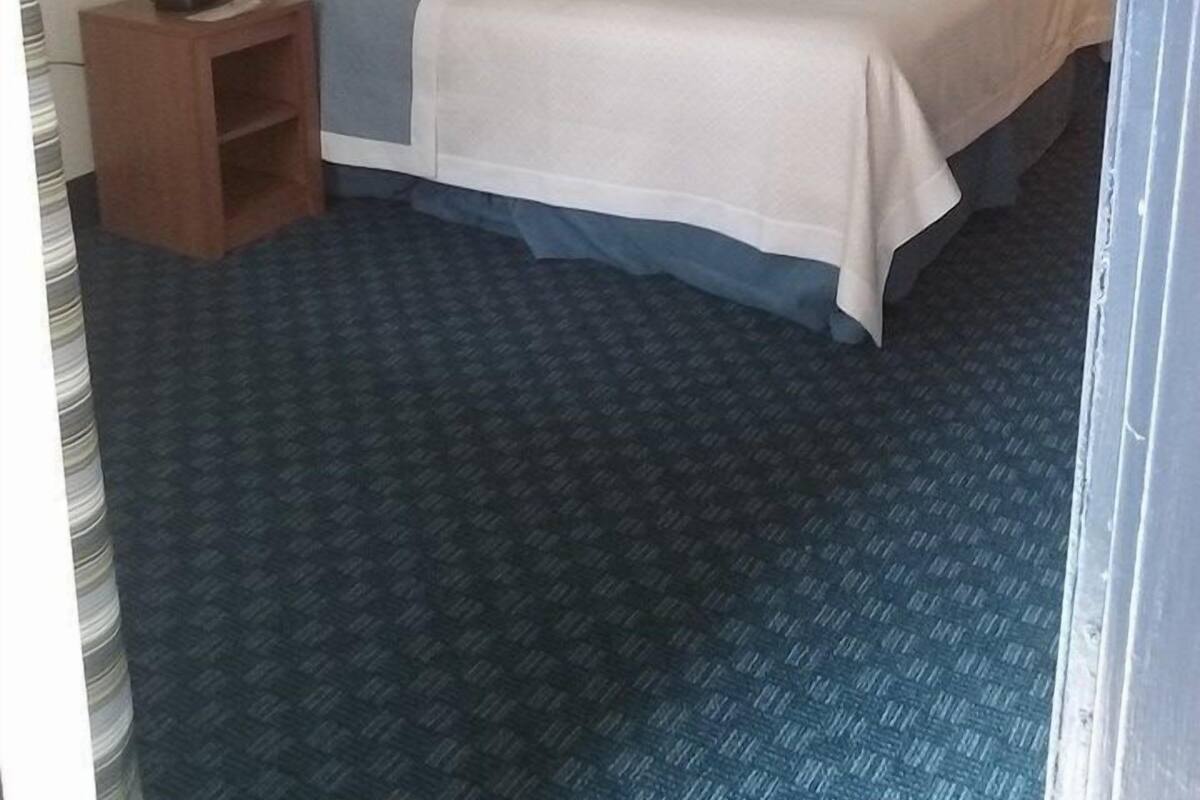 Una habitación de hotel estándar con cama, mesitas de noche y lámparas.