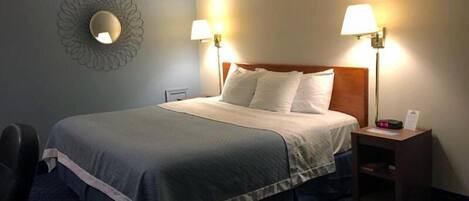 A hotel room with a bed, two bedside lamps, a nightstand, and a wall-mounted mirror.