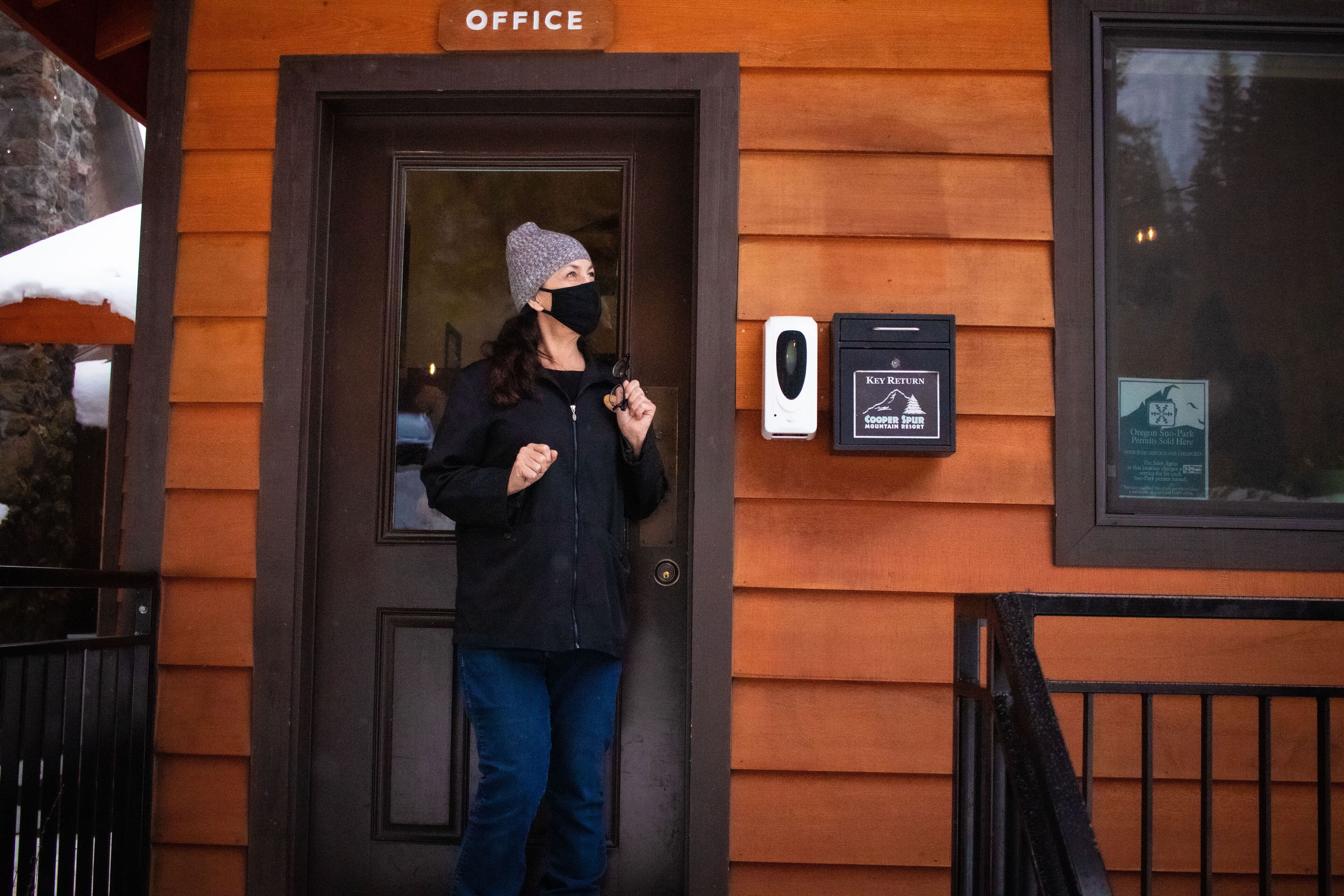 A person standing at the entrance of a building labeled "OFFICE" with a key card reader and a sign indicating key return.