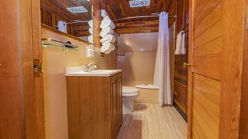 Un baño de madera con lavamanos, inodoro y cortina de ducha.