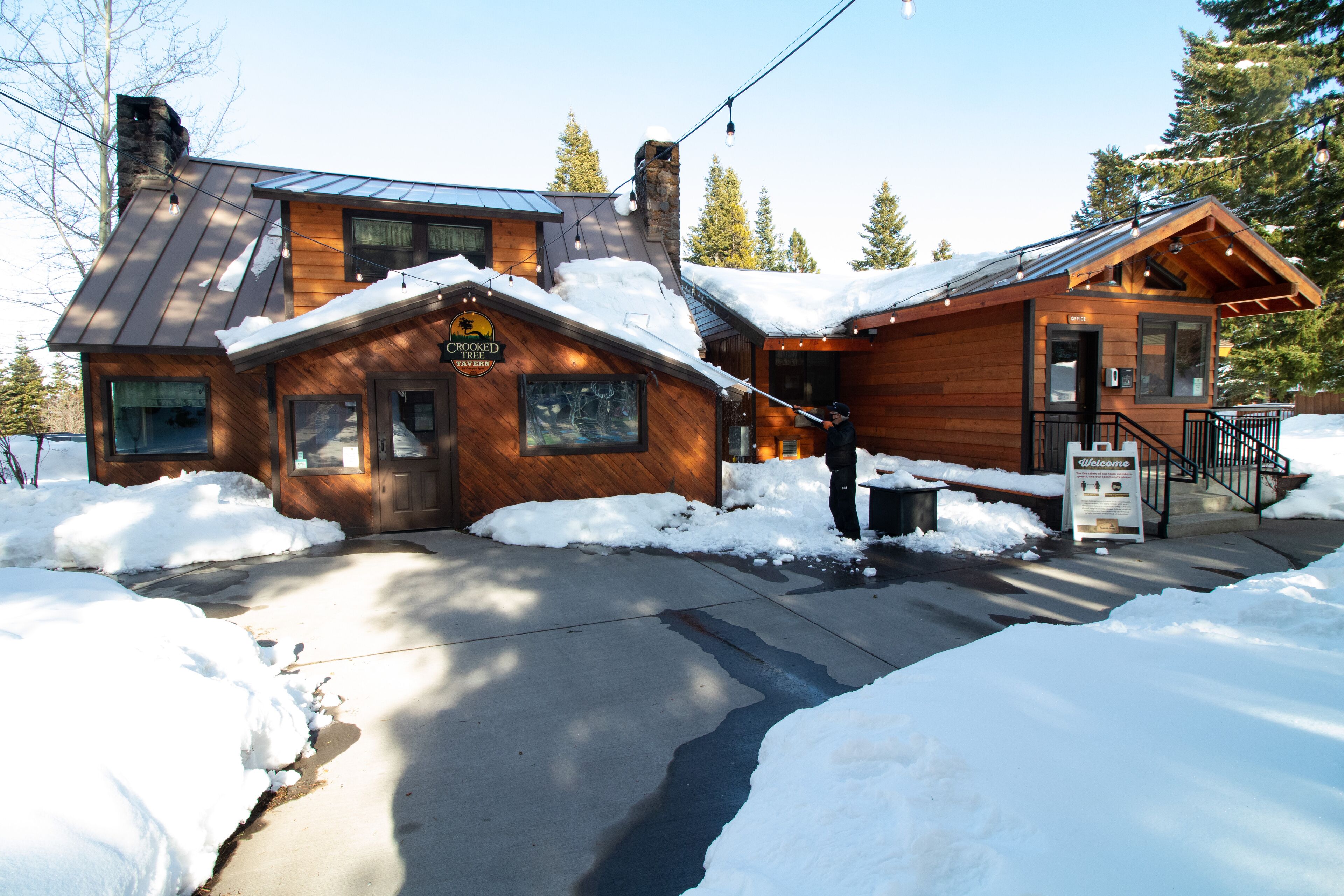 Una cabaña de madera con techo nevado y un letrero que dice "Crooked Creek Lodge".