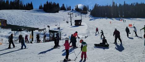 A ski resort with a chairlift, ski slopes, and a clear sky.