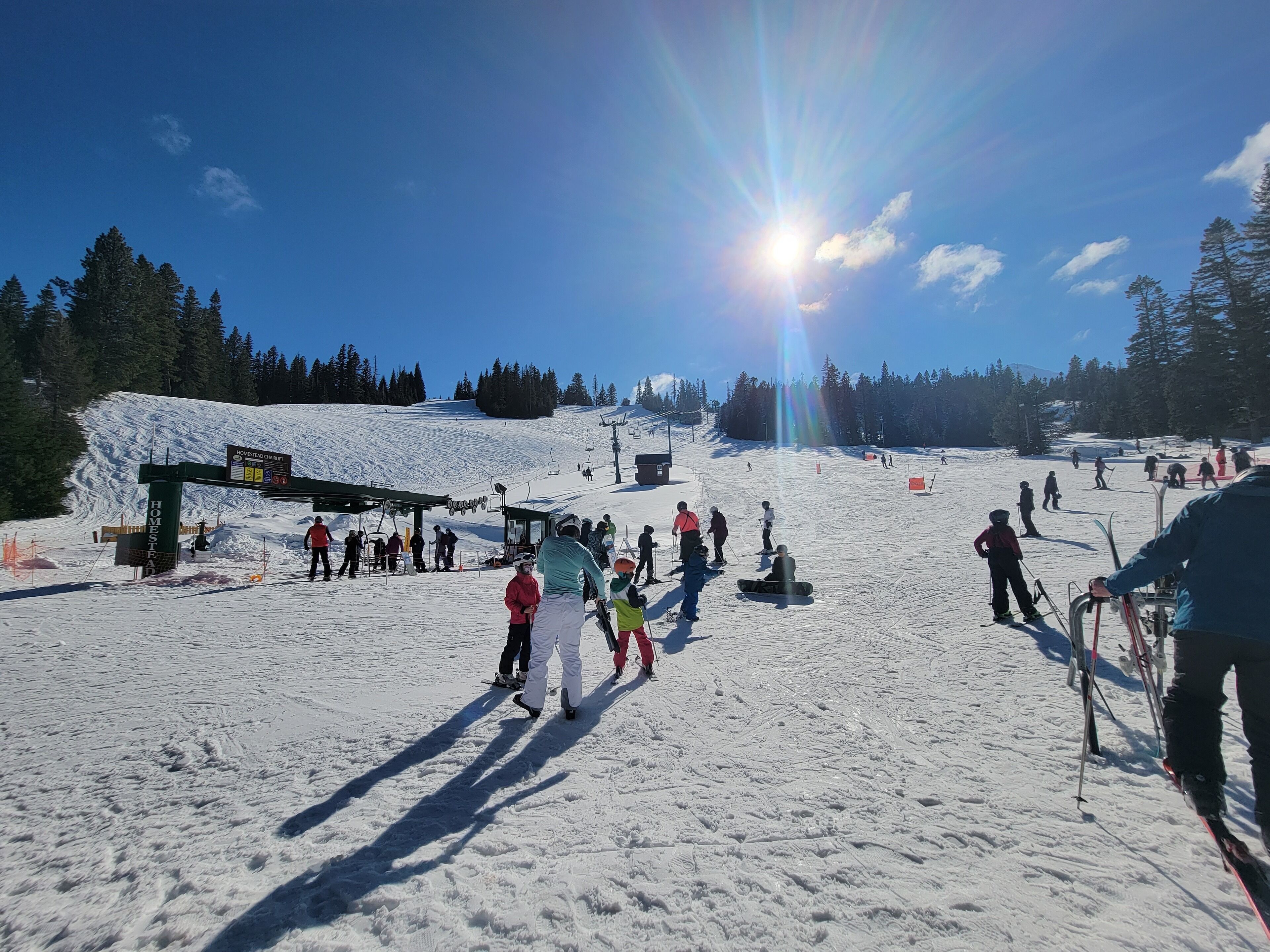 A ski resort with a chairlift, skiers, and a snow-covered slope.