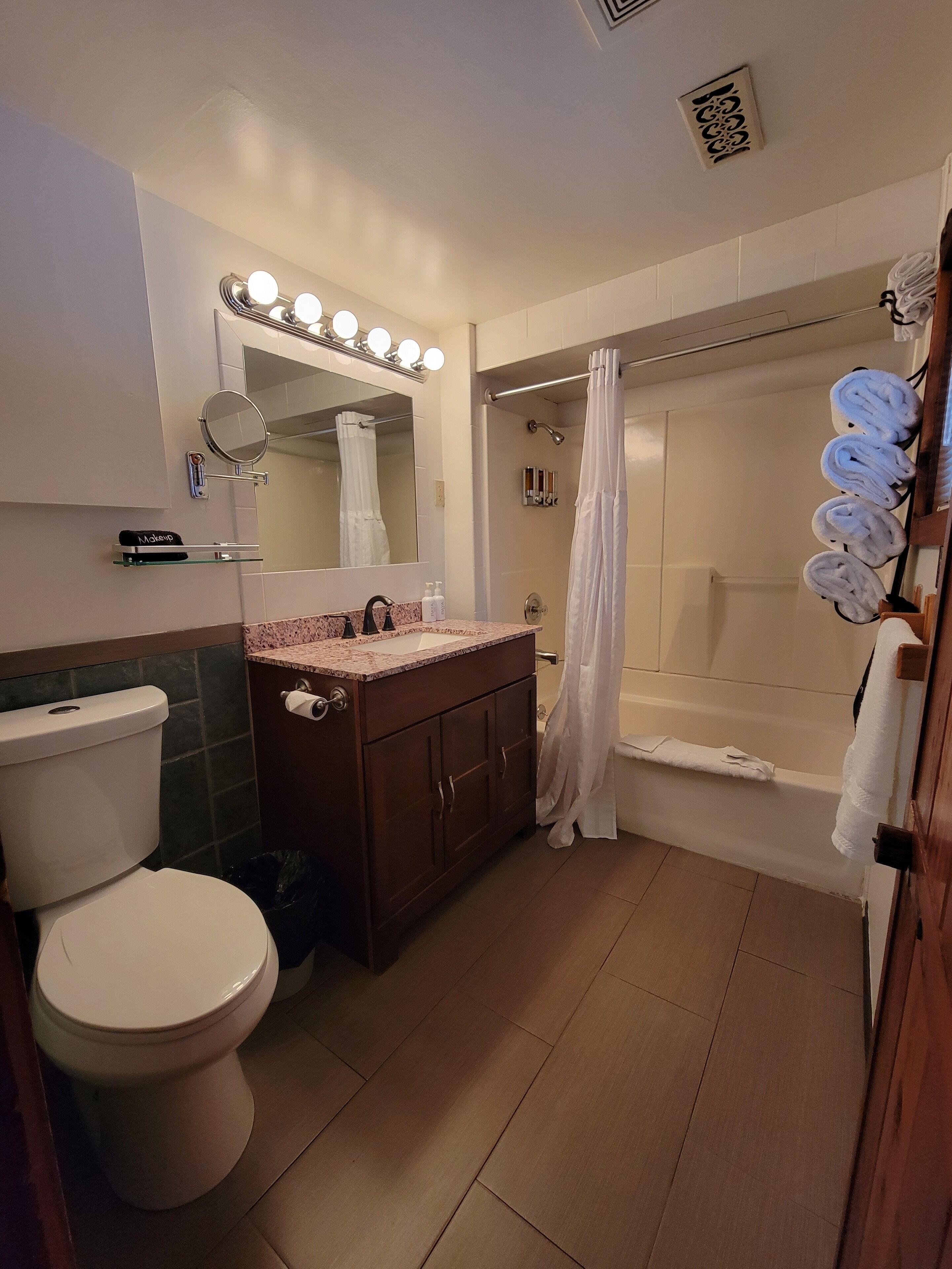 A bathroom with a toilet, sink, mirror, and shower.