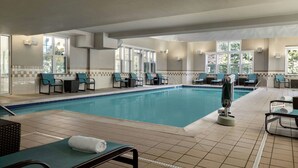 Una piscina interior con múltiples sillas de descanso y un sillón solárium.