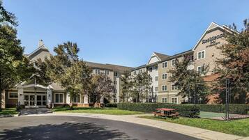 A multi-story hotel with a central entrance, outdoor seating, and a well-maintained lawn.