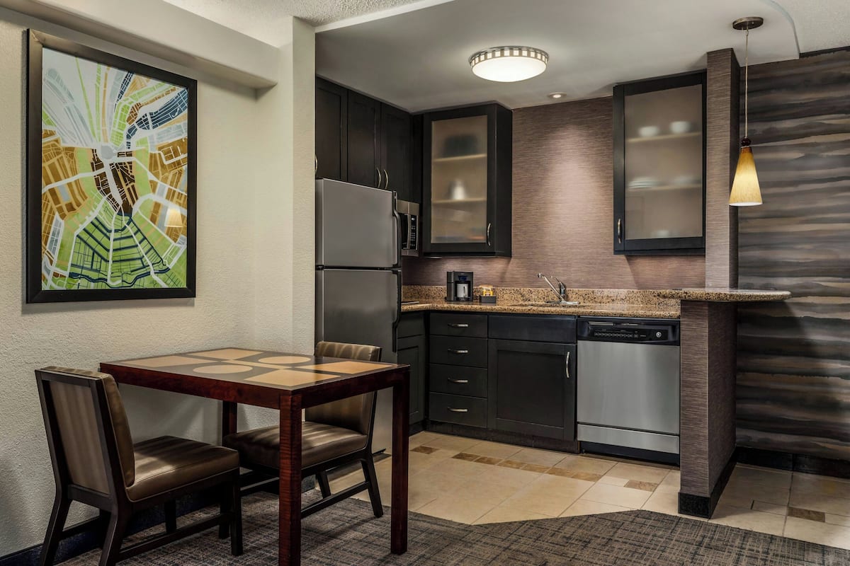 A modern kitchen with dark cabinets, stainless steel appliances, and a granite countertop.