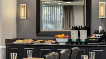 A hotel room with a breakfast bar, a large mirror, and a coffee station.