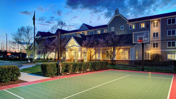 Un edificio residencial con una cancha de baloncesto al frente.