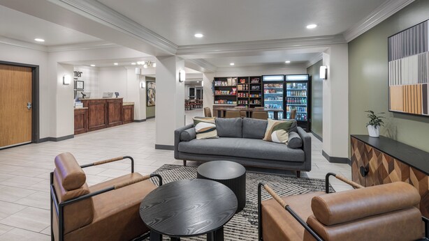 A spacious living area with a sofa, armchairs, a coffee table, and a bookshelf filled with books and decorative items.