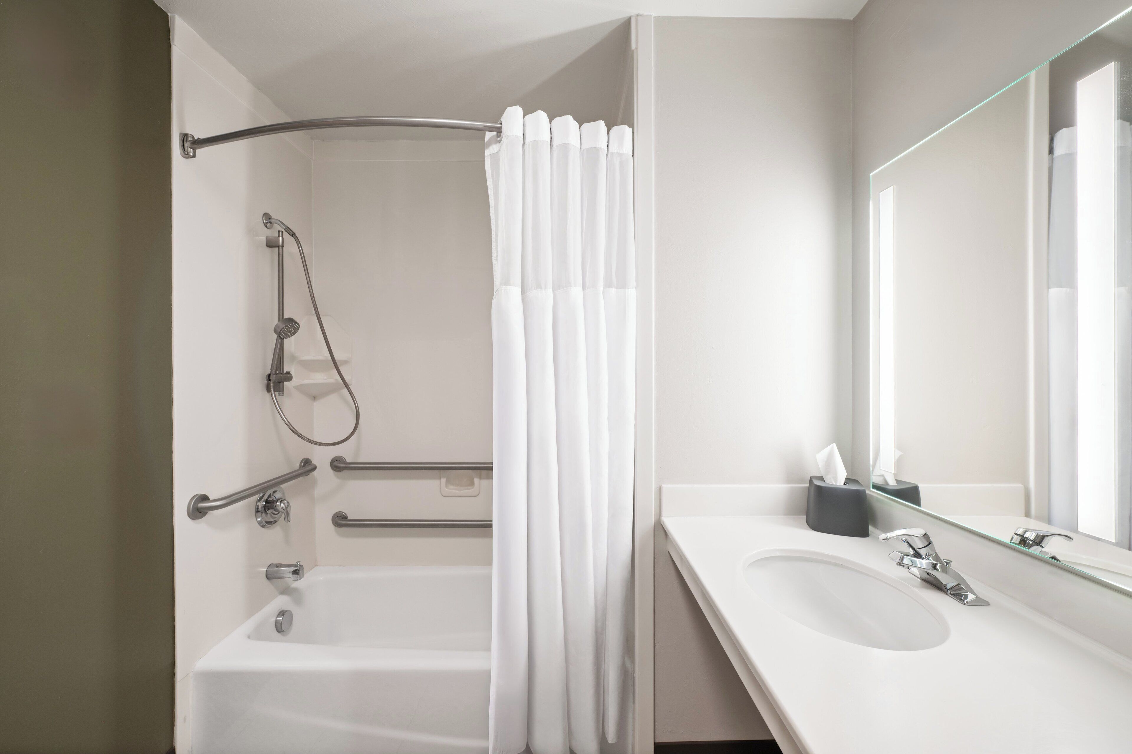 Un bagno moderno con vasca, doccia e un ampio specchio.