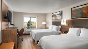 A hotel room with two beds, a desk, a chair, a TV, and a window with a view.