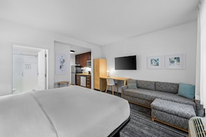 Una habitación de hotel con cama, sofá, escritorio, silla y televisión.