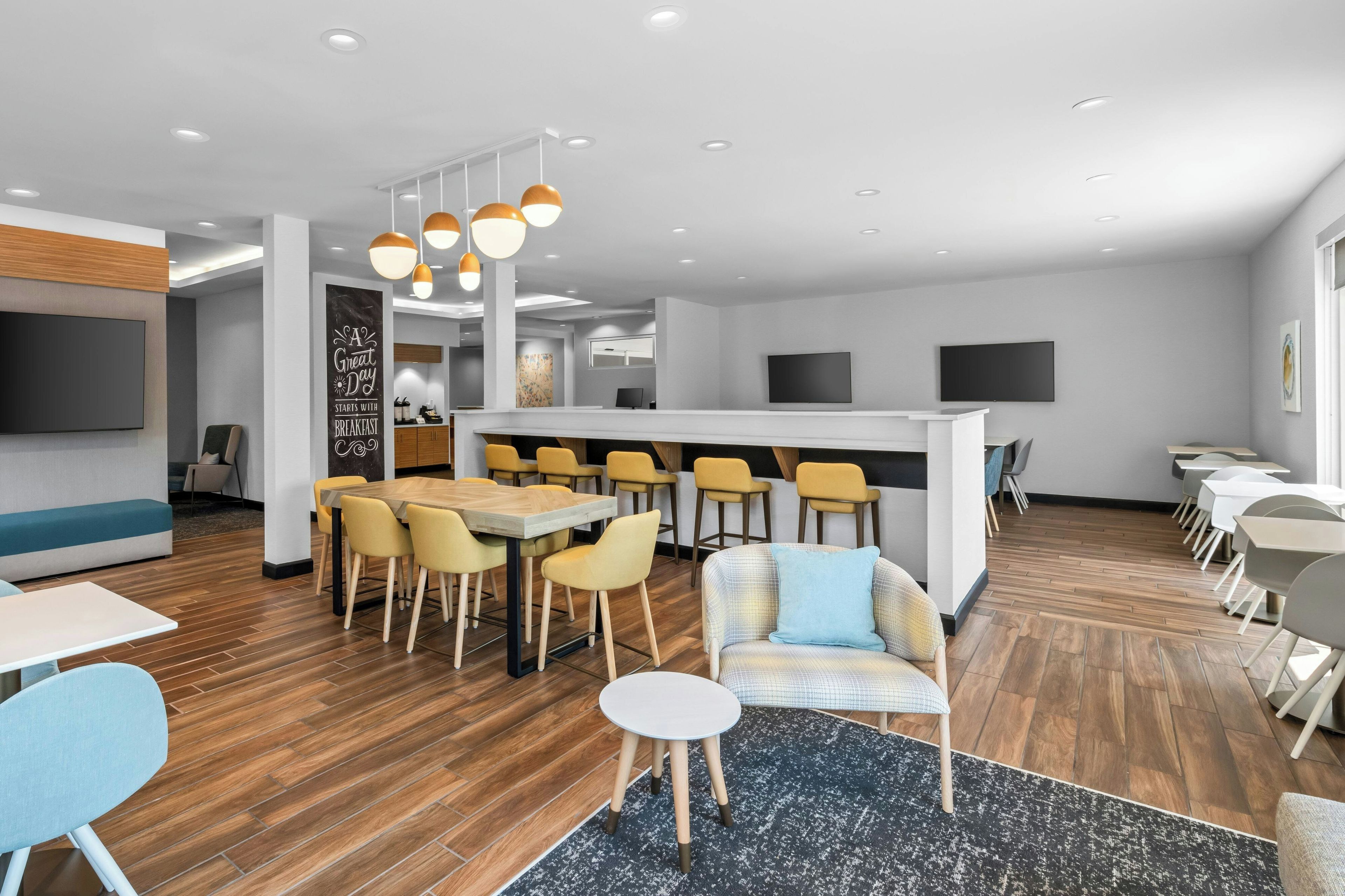 A modern interior with a bar area, multiple seating arrangements, and a large flat-screen TV.