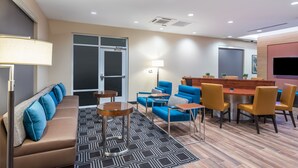 Una habitación de hotel moderna con sofá, sillones, una mesita y televisor.