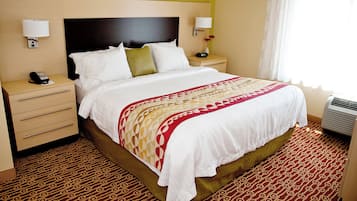 Habitación de hotel con una cama grande, dos mesitas de noche, un teléfono y una lámpara de pared.