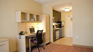 Habitación de hotel con escritorio, silla y kitchenette.