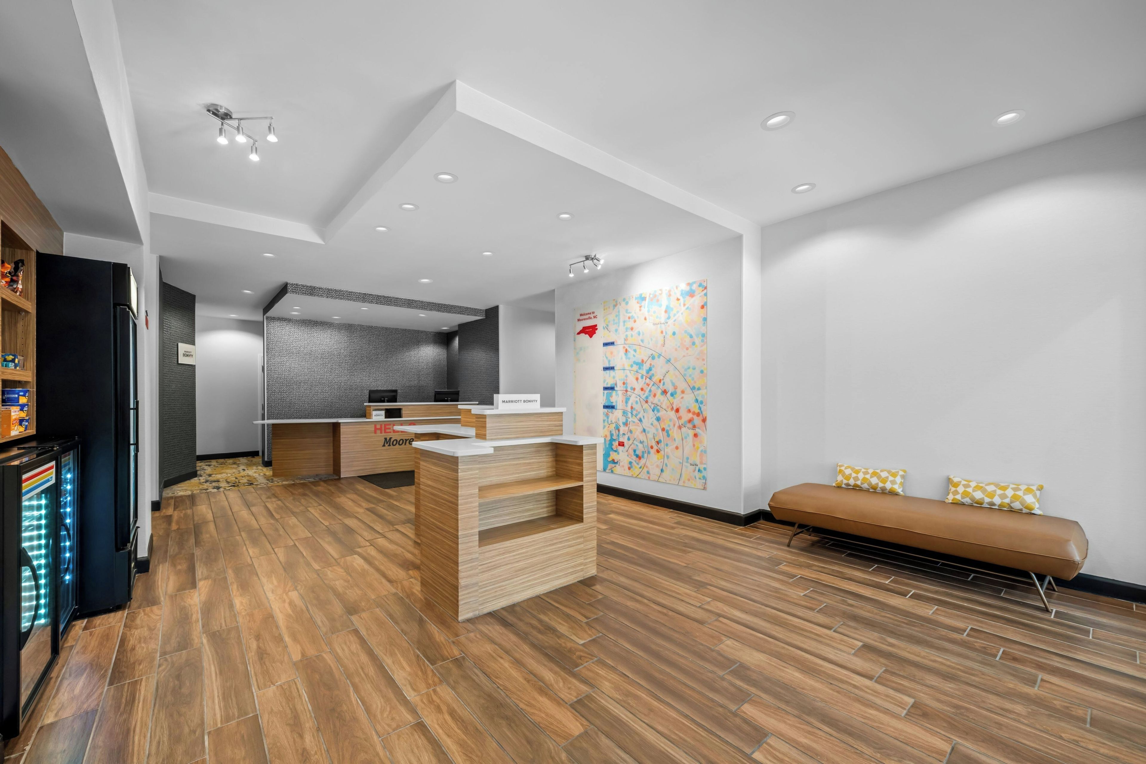 Un hall d’hôtel comprenant un comptoir d’accueil, un espace salon et un mur orné d’une carte aux couleurs vives.