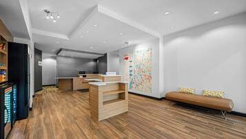 Un hall d’hôtel comprenant un comptoir d’accueil, un espace salon et un mur orné d’une carte aux couleurs vives.